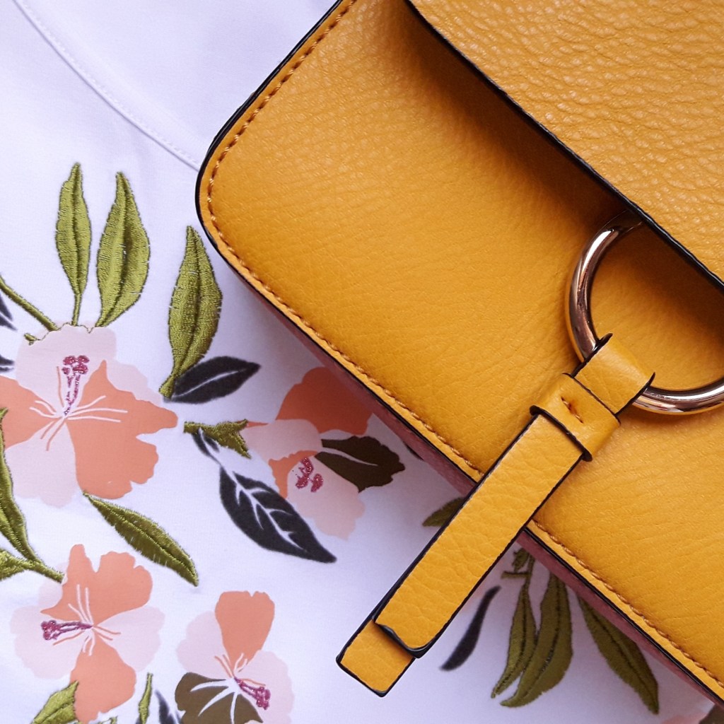 Bolso amarillo sobre una camiseta de flores